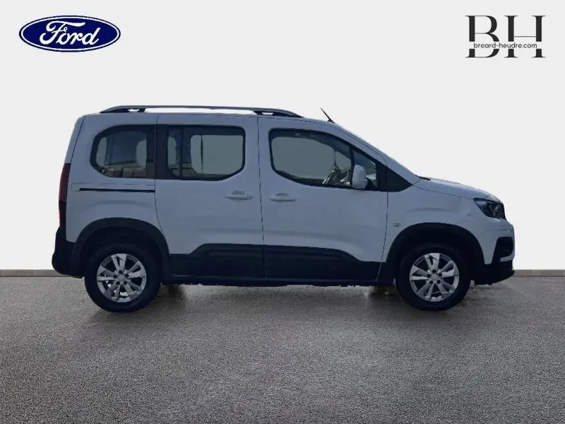 Vue de profil droit d'un Peugeot Rifter blanc avec barres de toit et jantes alliage 16 pouces.