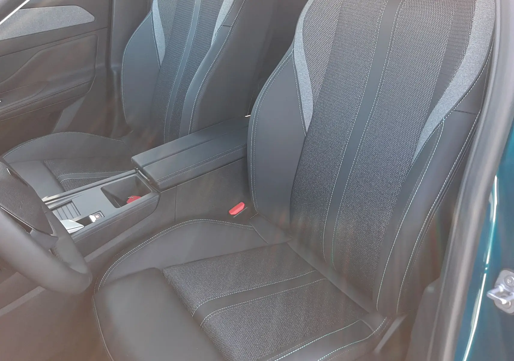 Vue intérieure côté conducteur de la Peugeot 308 2025 Bleu Obsession, sièges tissu et cuir noir avec surpiqûres bleues.