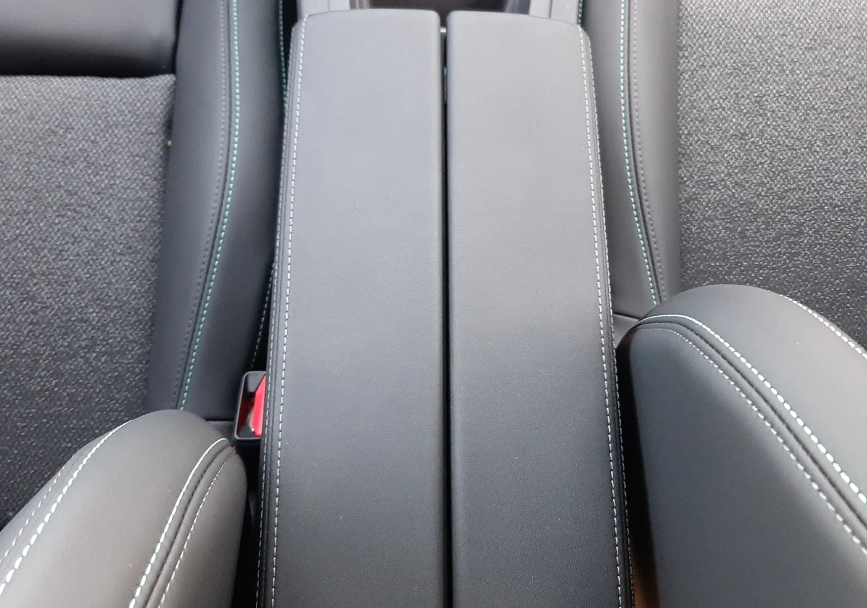 Vue plongeante sur l'accoudoir central en cuir noir avec surpiqûres blanches de la Peugeot 308 Bleu Obsession 2025.