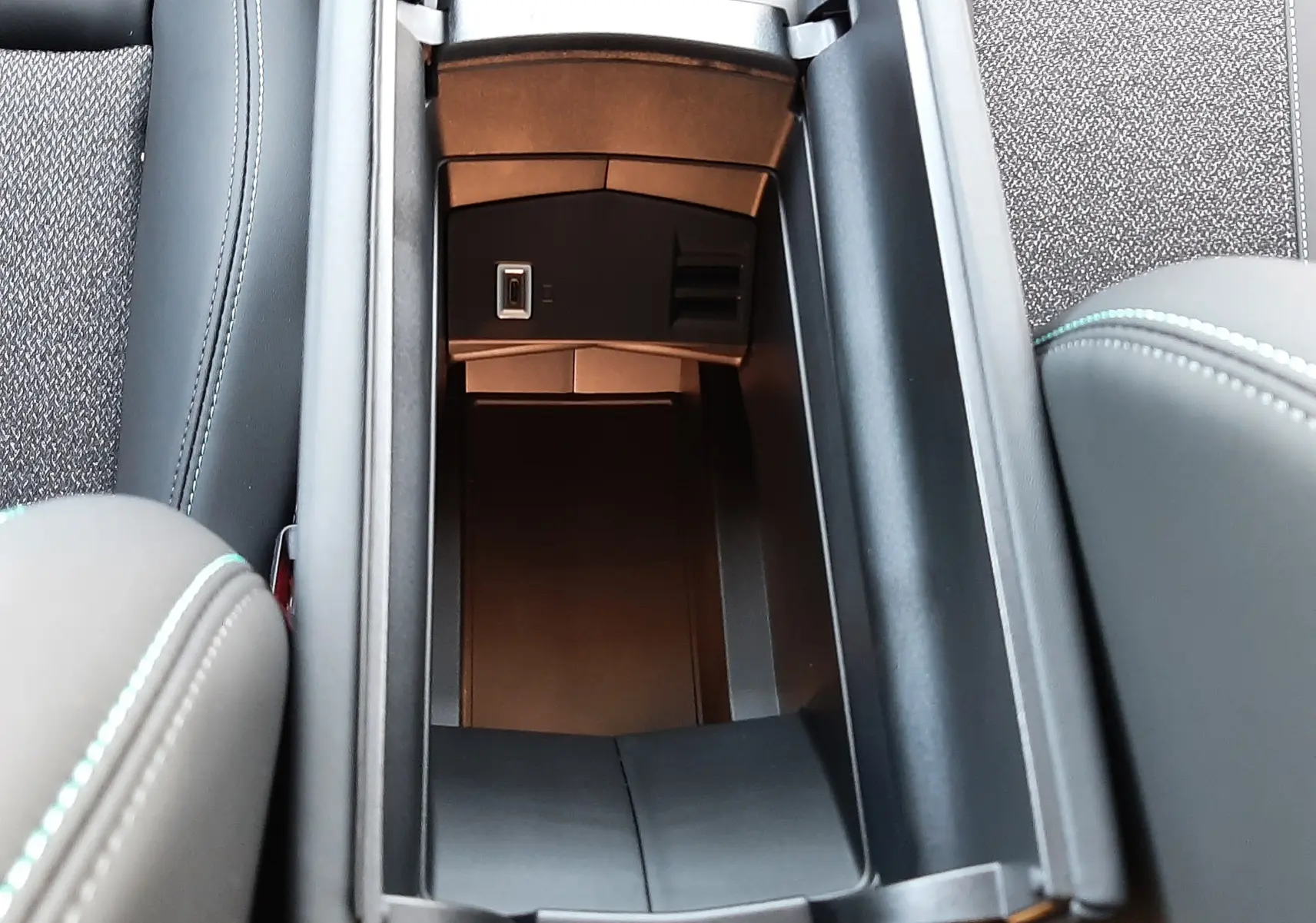 Vue plongeante sur le rangement central ouvert de la Peugeot 308 BlueHDi 130ch, intérieur noir avec coutures contrastées.