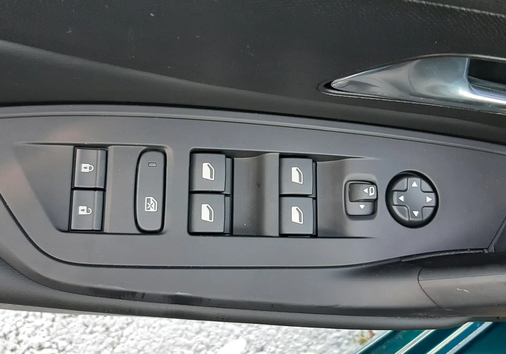 Vue rapprochée des commandes de lève-vitres et rétroviseurs sur la porte côté conducteur d'une Peugeot 308 Bleu Obsession.