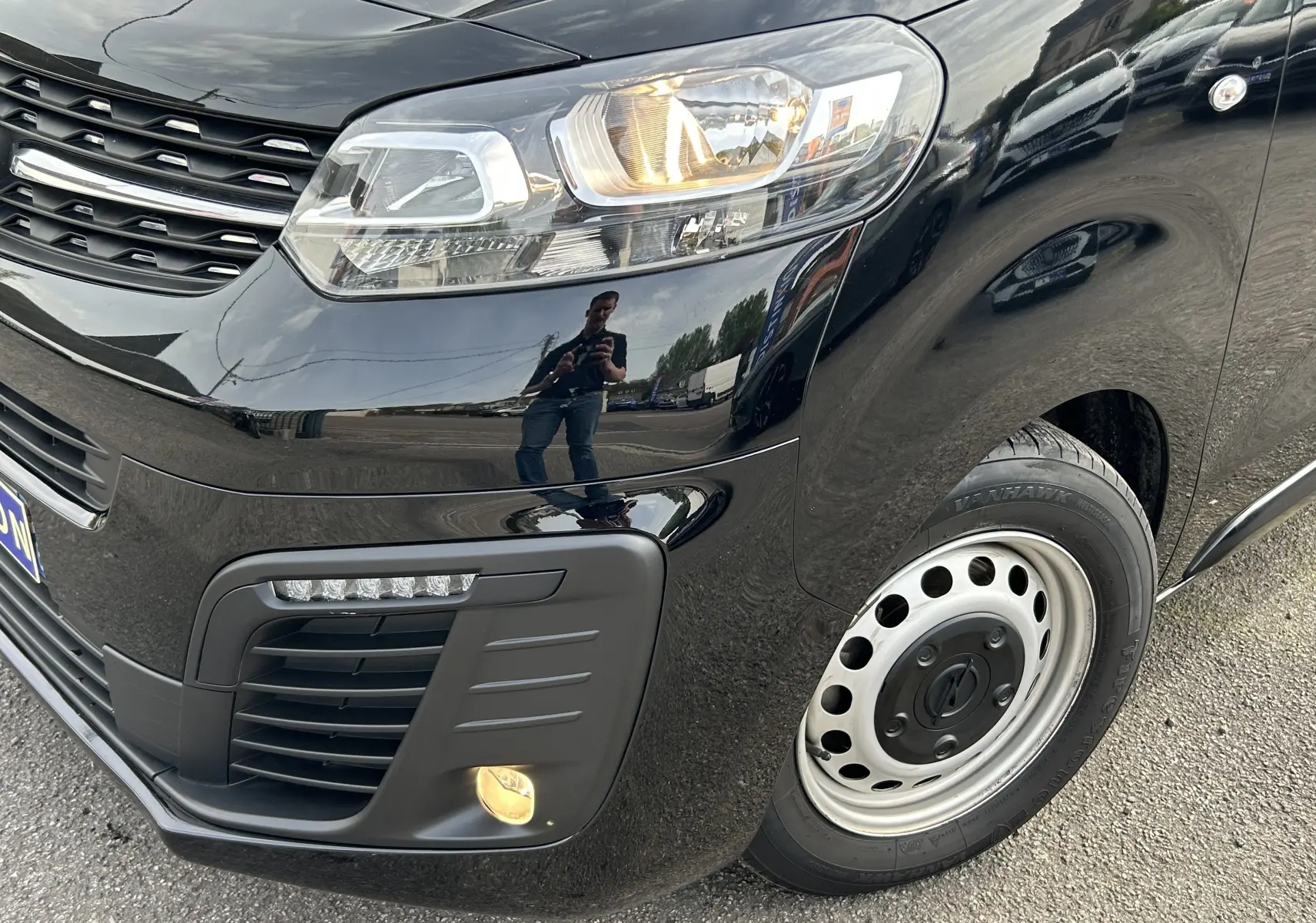 Gros plan sur l’avant droit noir d’un Opel Vivaro Combi 2022 avec phare allumé et jante acier visible.