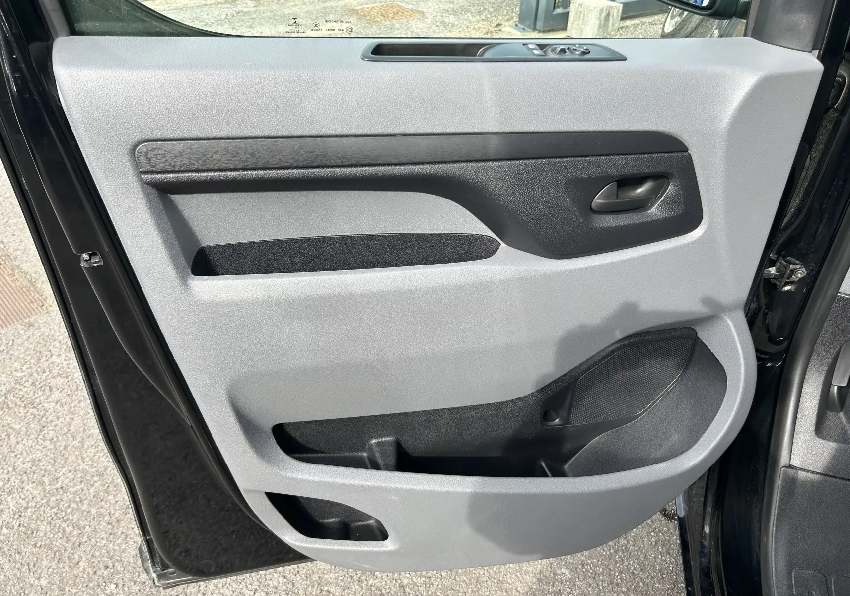 Vue rapprochée de la porte avant gauche noire de l’Opel Vivaro Combi 2022, avec panneau intérieur gris et noir.
