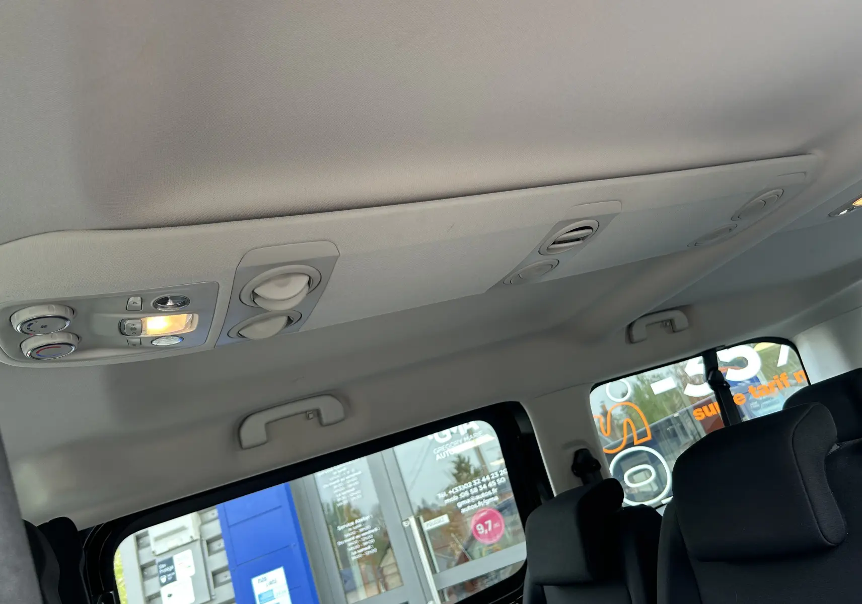 Vue intérieure du plafond et des aérations arrière du Opel Vivaro Combi noir, avec sièges en tissu visibles en partie.