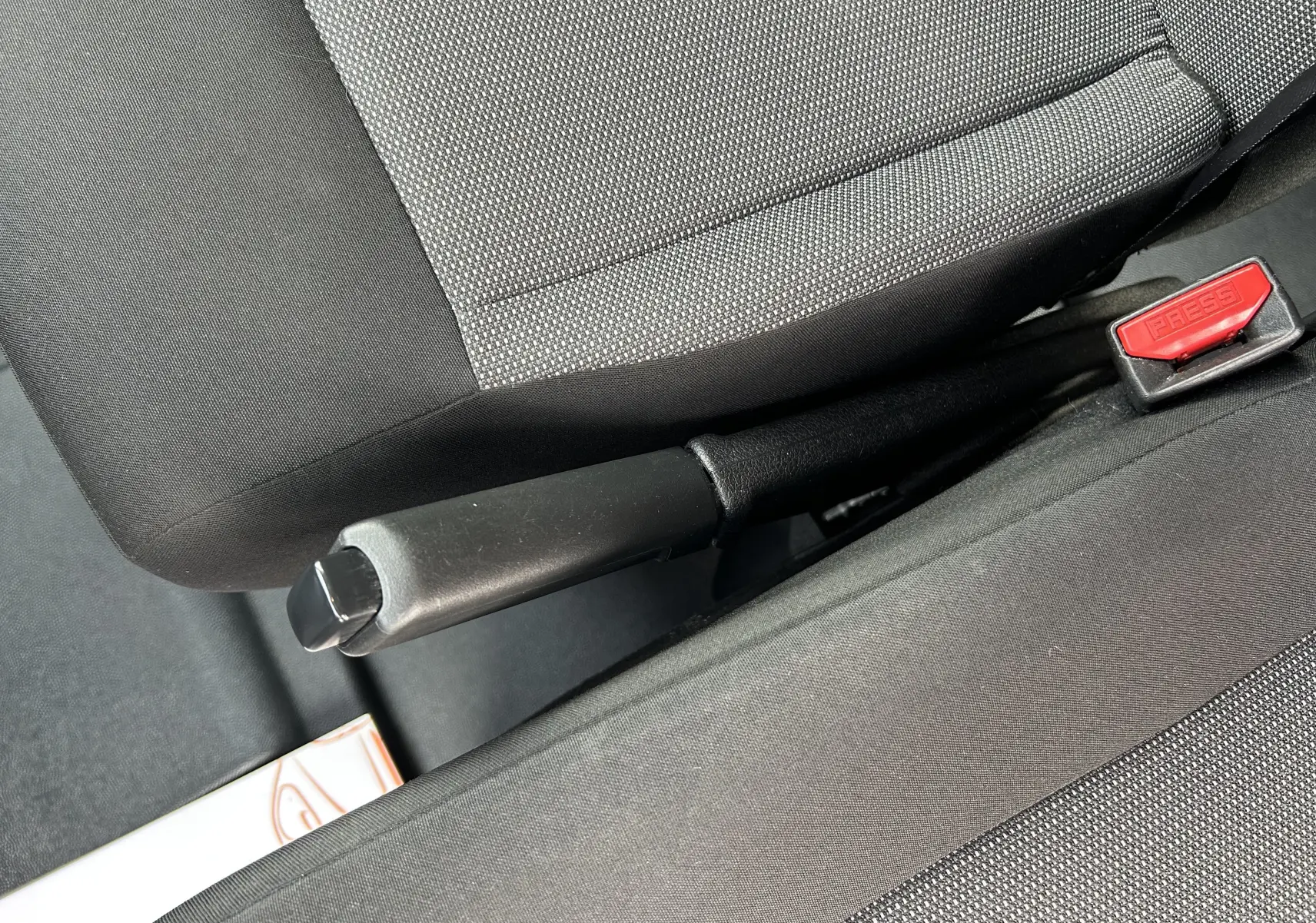 Vue rapprochée de la poignée de frein à main entre les sièges avant en tissu gris et noir de l’Opel Vivaro Combi noir.