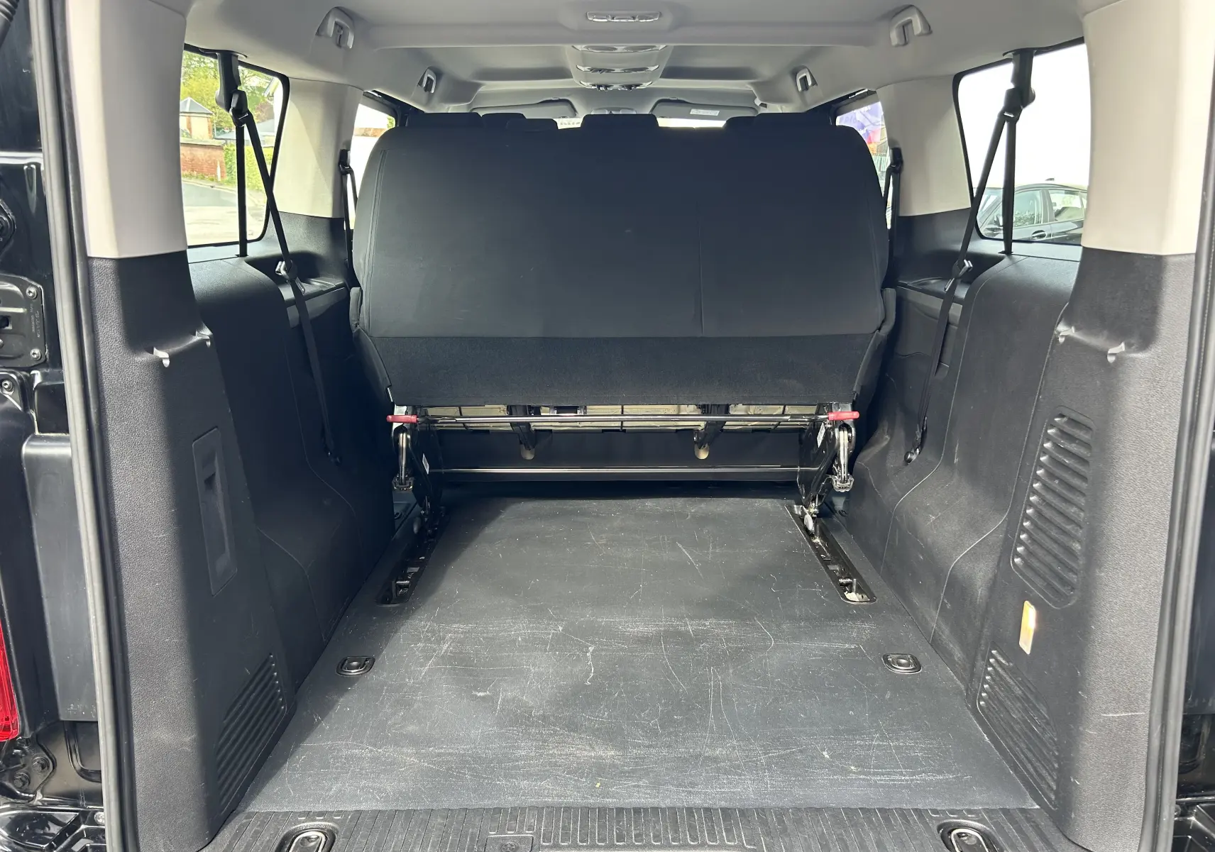 Vue arrière de l’intérieur noir d’un Opel Vivaro Combi Zafira Life L3 2022 avec banquette arrière relevée et espace de chargement visible.