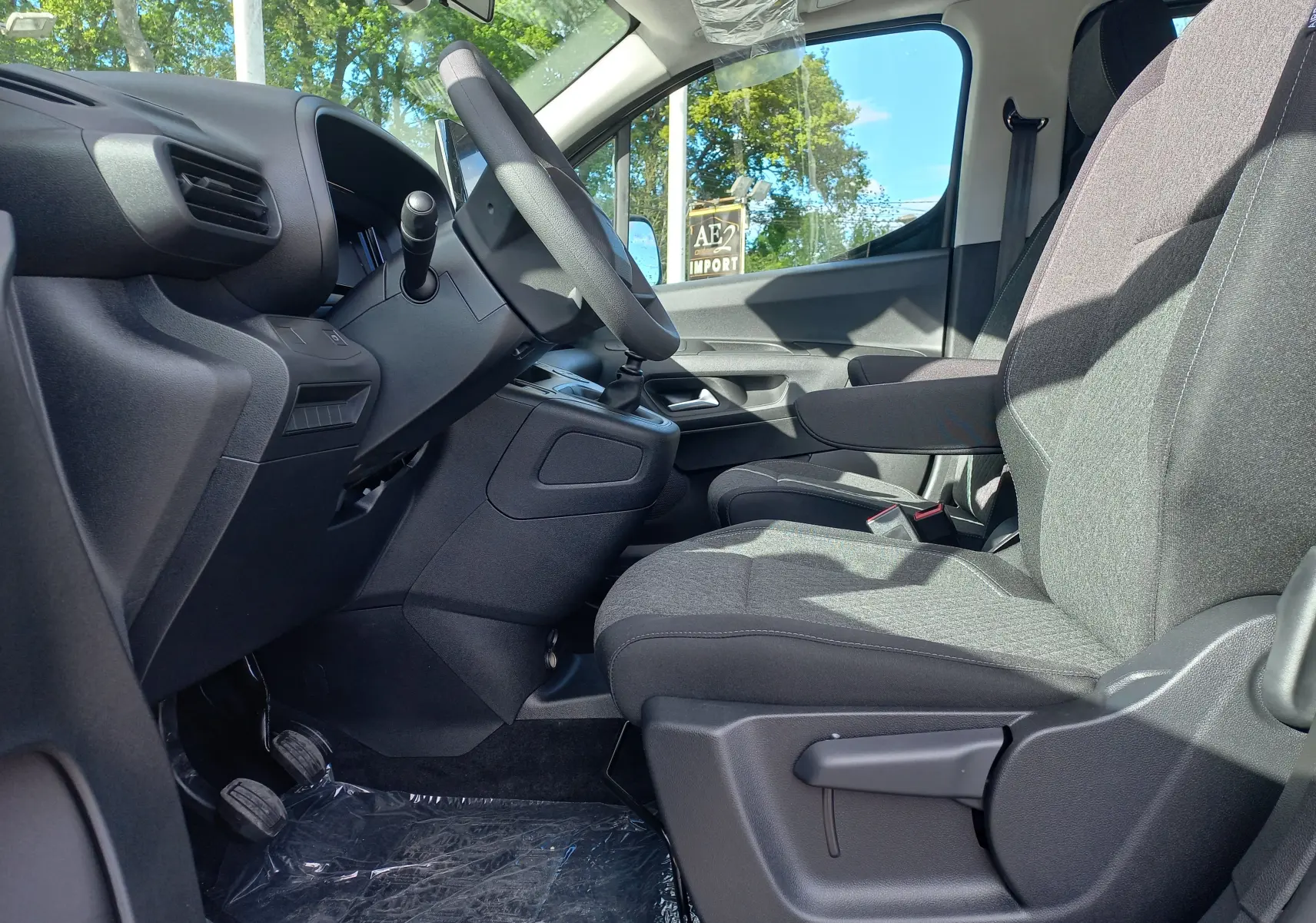 Vue intérieure côté conducteur de l’Opel Combo Life 2025, sièges gris et tableau de bord noir, volant cuir visible.