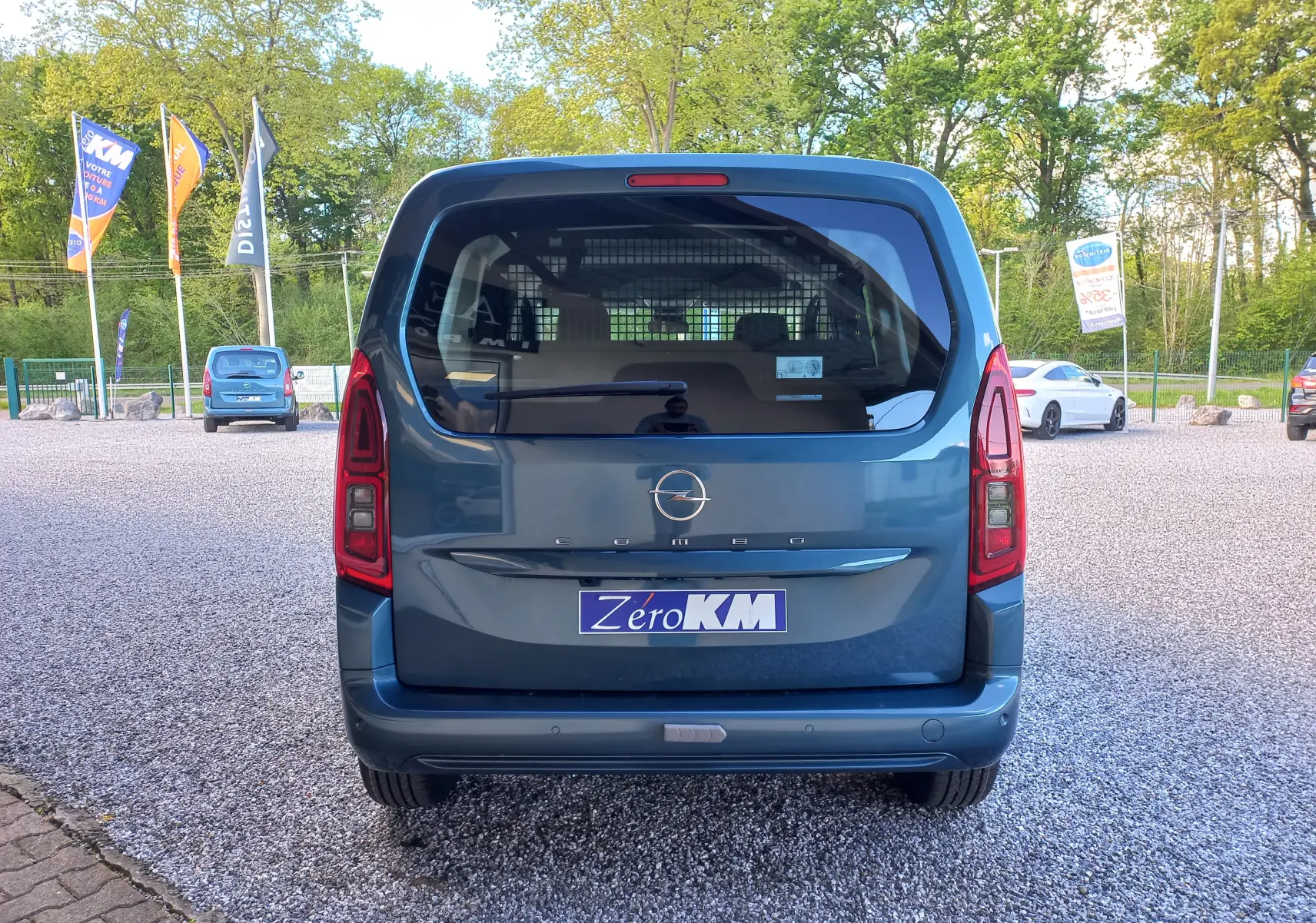 Vue arrière d’un Opel Combo Life bleu Kiama 2025 avec hayon vitré et feux arrière verticaux, stationné sur un parking.