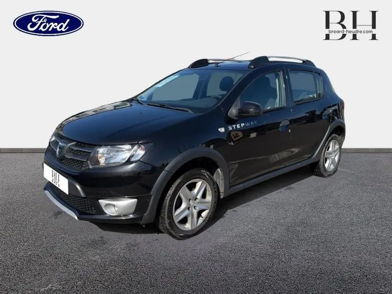 Dacia Sandero Stepway noir nacré vue 3/4 avant droit avec barres de toit et jantes alliage.