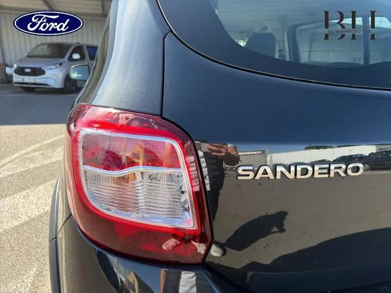 Gros plan sur l'arrière droit noir nacré d'une Dacia Sandero avec feu arrière et logo visible.