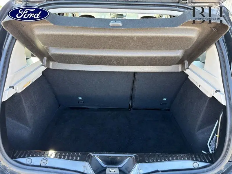 Coffre ouvert vu de l'arrière d'une Dacia Sandero noir nacré, montrant un espace de chargement vide et propre.