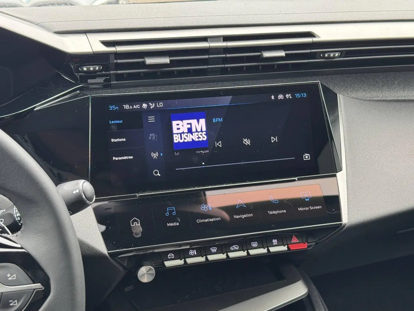 Vue intérieure du tableau de bord de la Peugeot 308 Hybrid 2025, écran tactile multifonction affichant BFM Business.