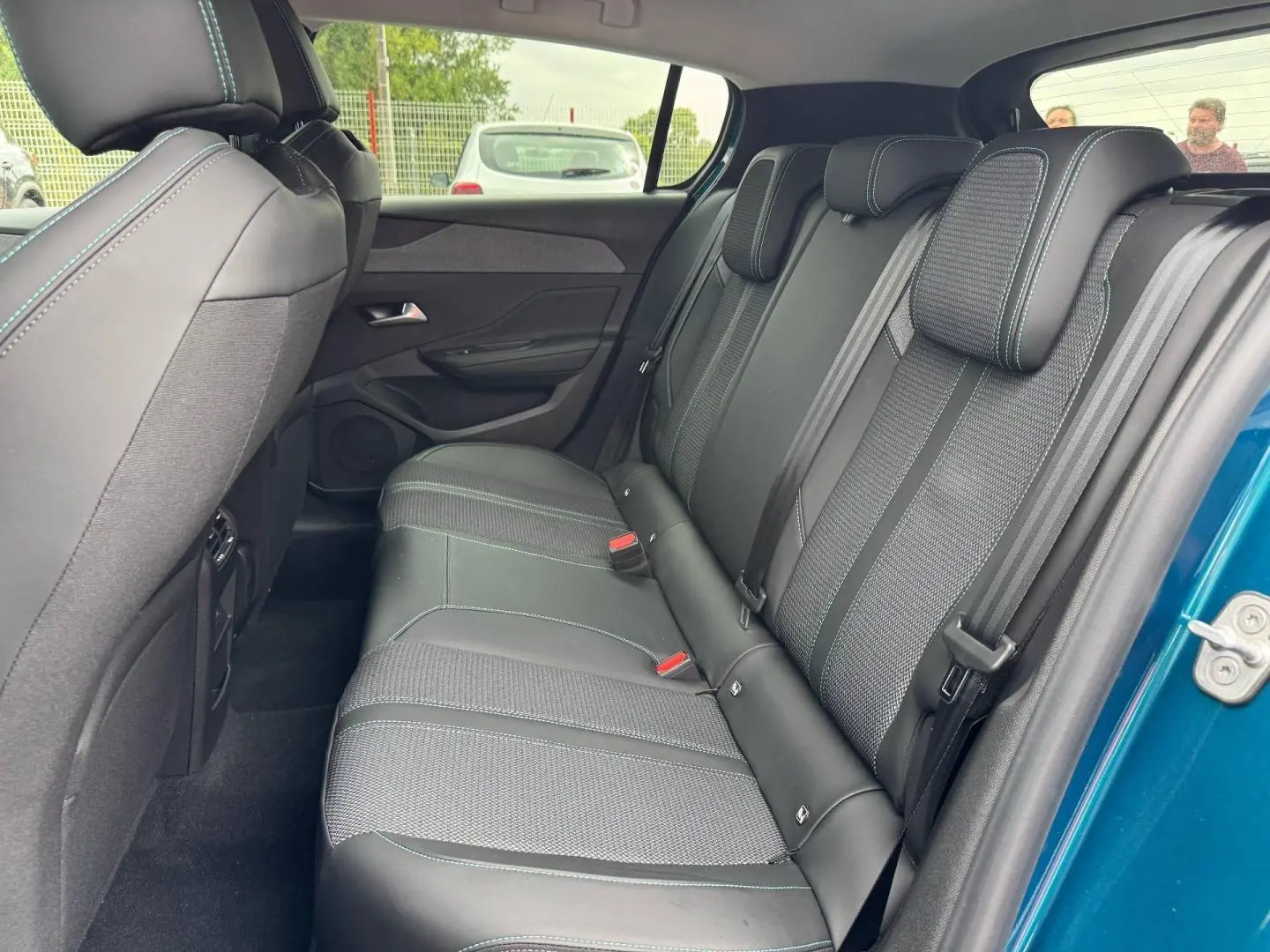 Vue latérale droite de la banquette arrière en tissu et cuir noir du Peugeot 308 bleu 2025, avec ceintures et appuie-têtes.