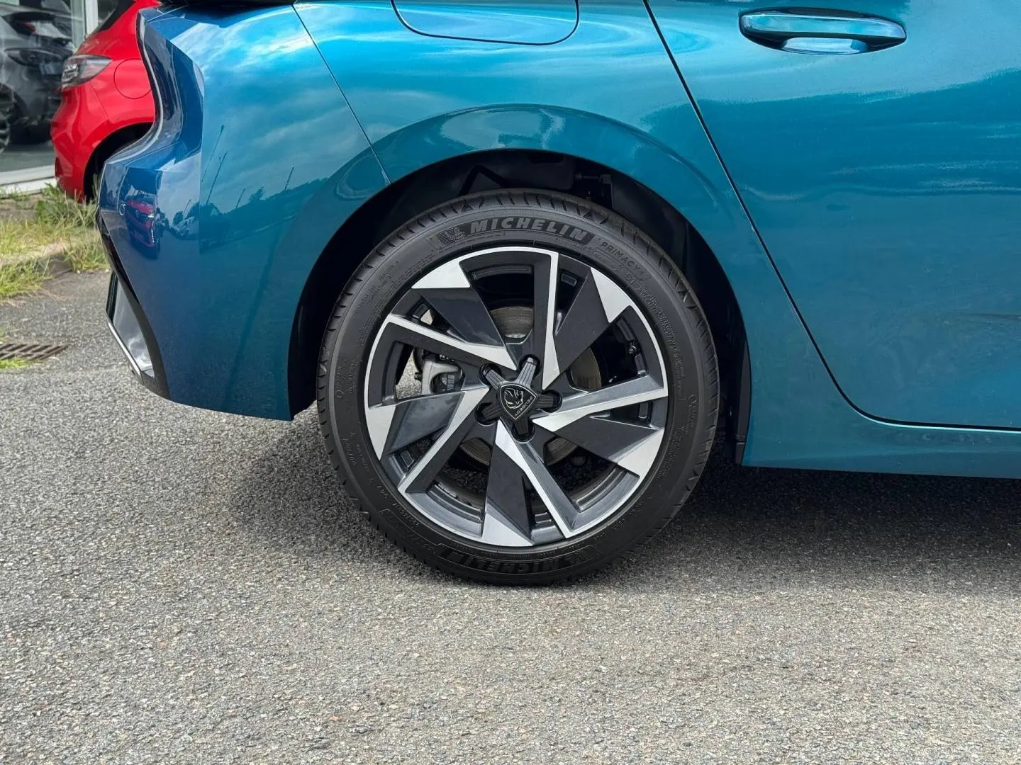Gros plan sur la roue arrière gauche d'une Peugeot 308 bleu Obsession 2025 avec jante alu au design moderne.