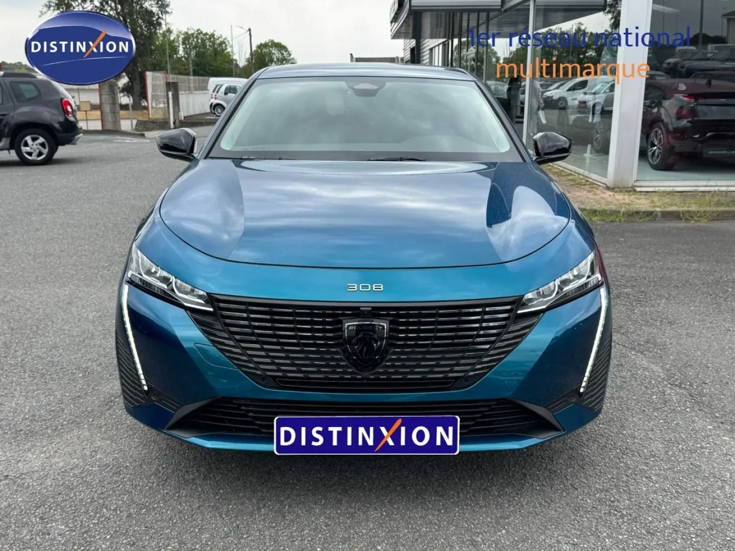 Vue avant d'une Peugeot 308 bleu Obsession 2025 avec calandre noire et feux LED verticaux allumés.