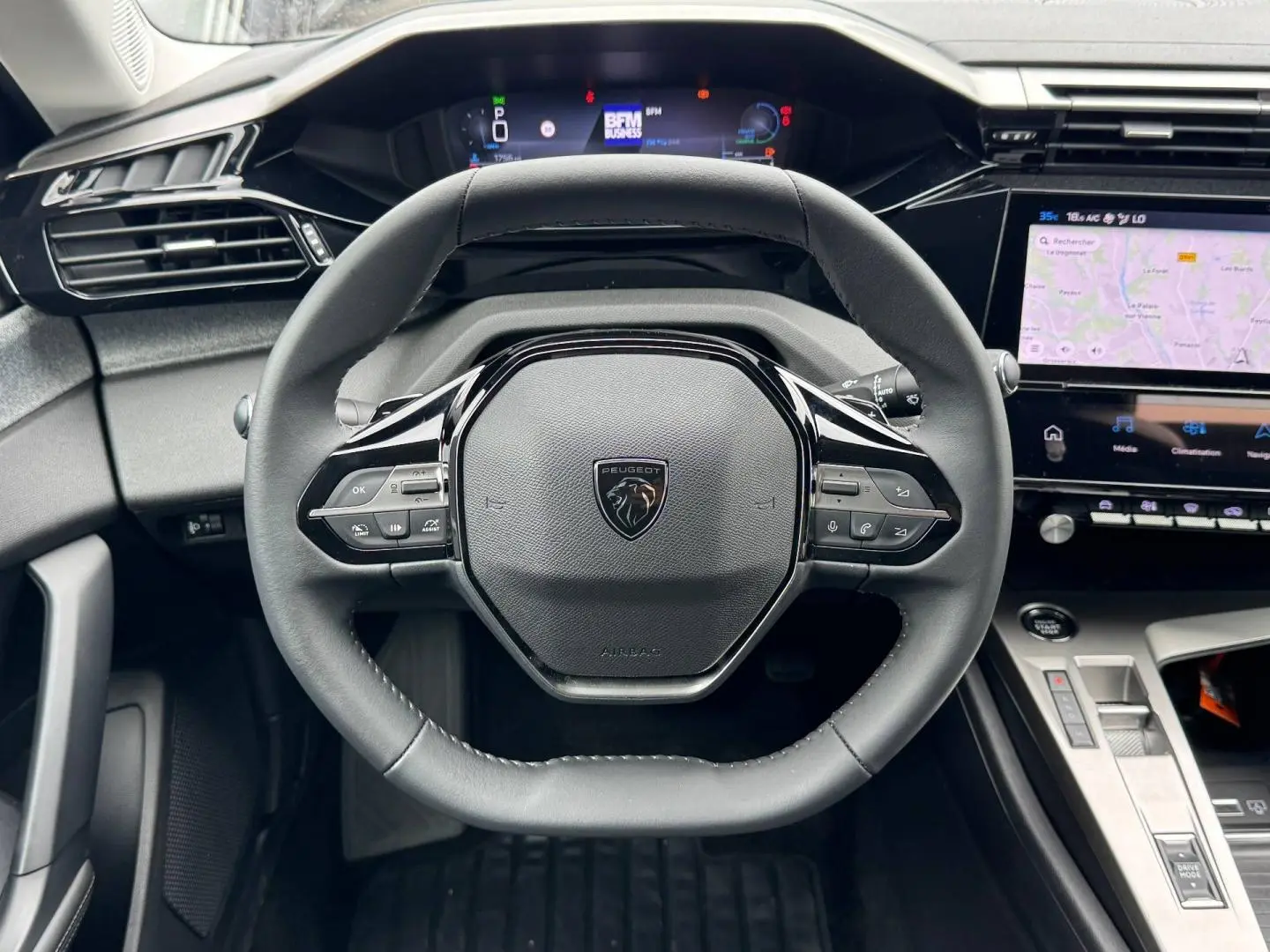 Vue frontale du volant cuir noir de la Peugeot 308 1.2 Hybrid 145ch avec tableau de bord numérique et écran tactile.
