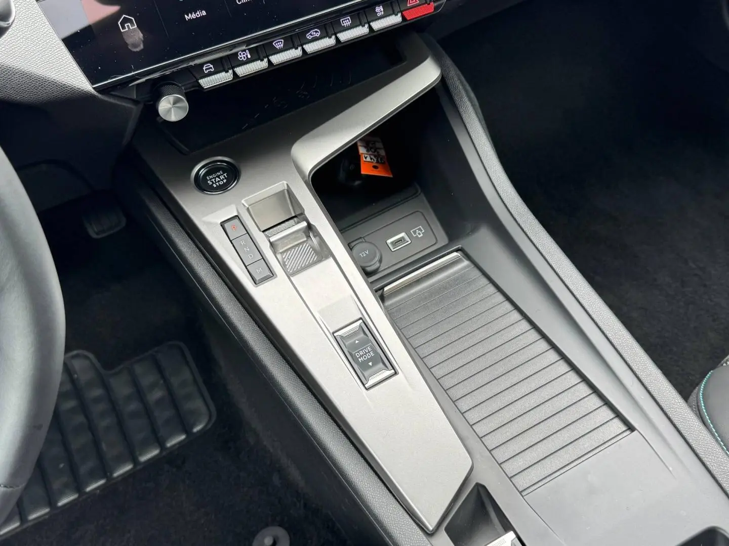Vue rapprochée de la console centrale grise avec levier de vitesses et bouton start/stop du Peugeot 308 hybride 2025.