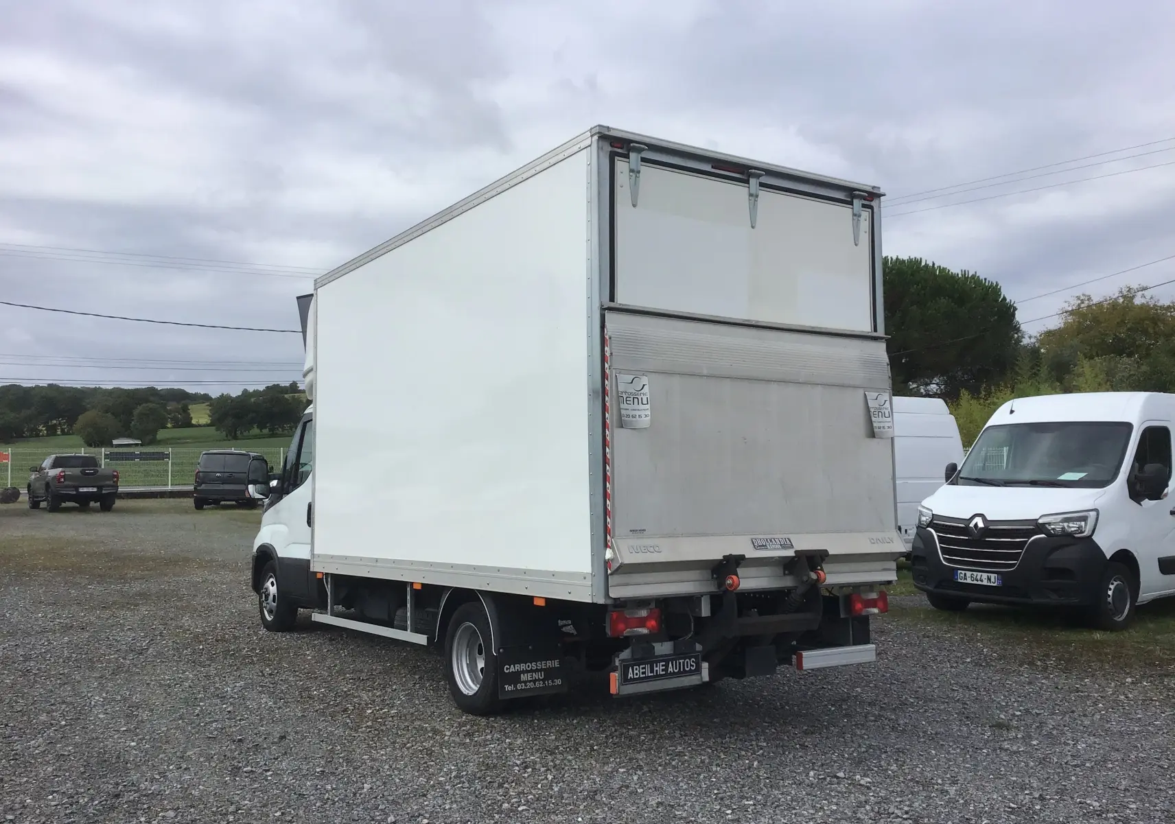 IVECO Daily Chassis Cabine blanc vu de l'arrière droit avec caisse 20m3 et hayon élévateur déployé.