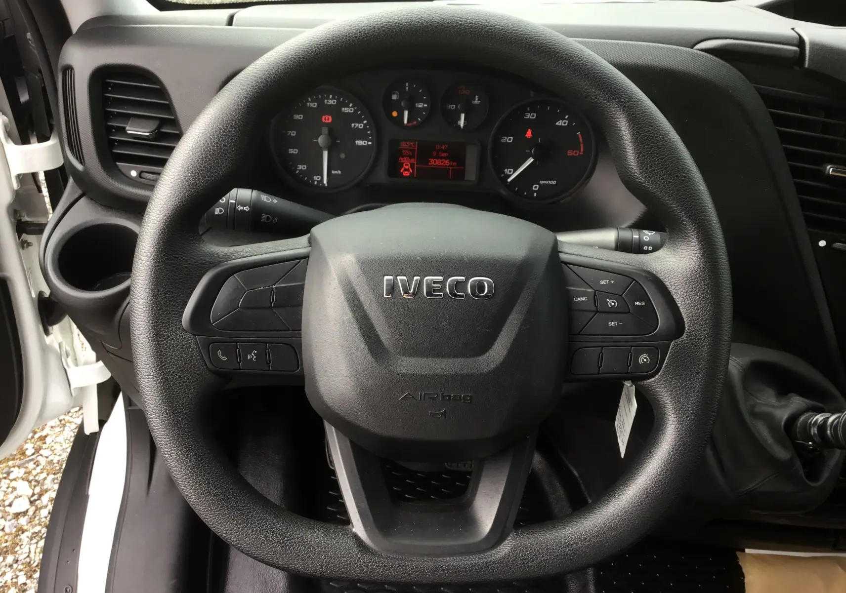 Vue rapprochée du volant noir IVECO et du tableau de bord du Daily Chassis Cabine blanc, avec commandes au volant visibles.