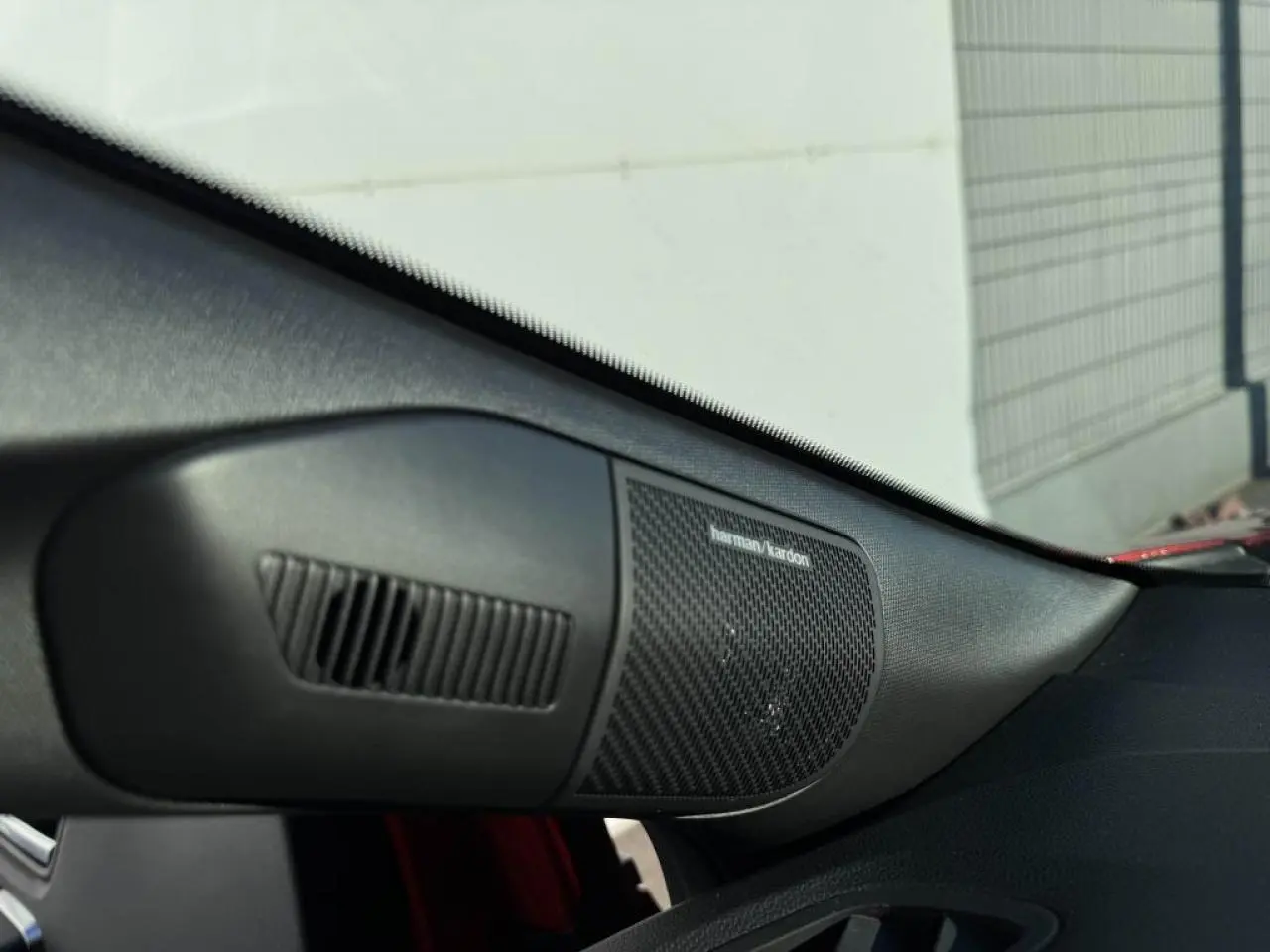Gros plan sur l'enceinte Harman Kardon côté passager d'un Renault Captur II rouge flamme toit noir.
