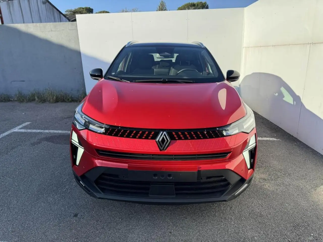 Vue frontale du Renault Captur II rouge flamme avec toit noir, mettant en valeur la calandre et les phares LED distinctifs.