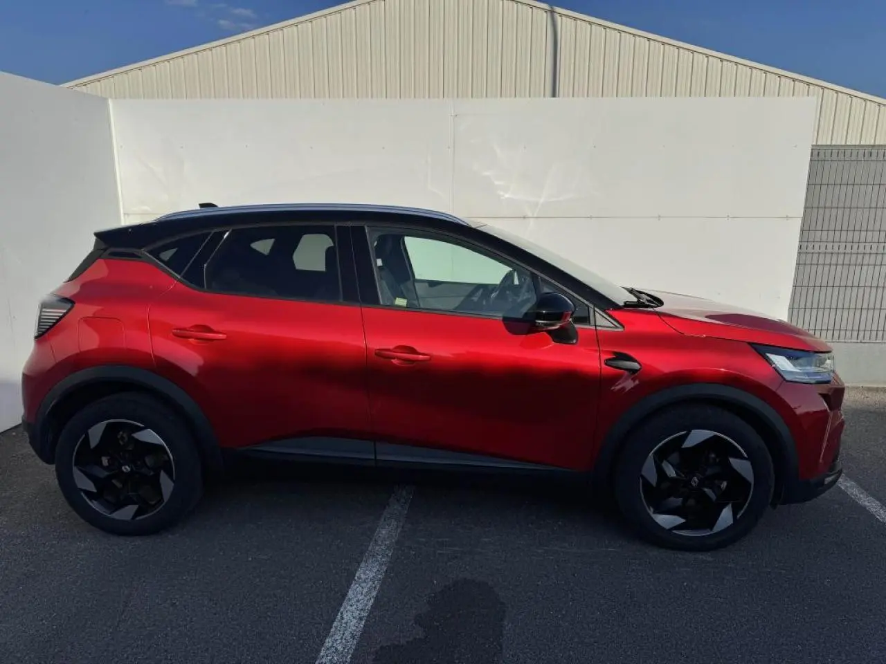 Profil côté gauche du Renault Captur II 2025 rouge flamme avec toit noir étoilé et jantes aluminium noires.