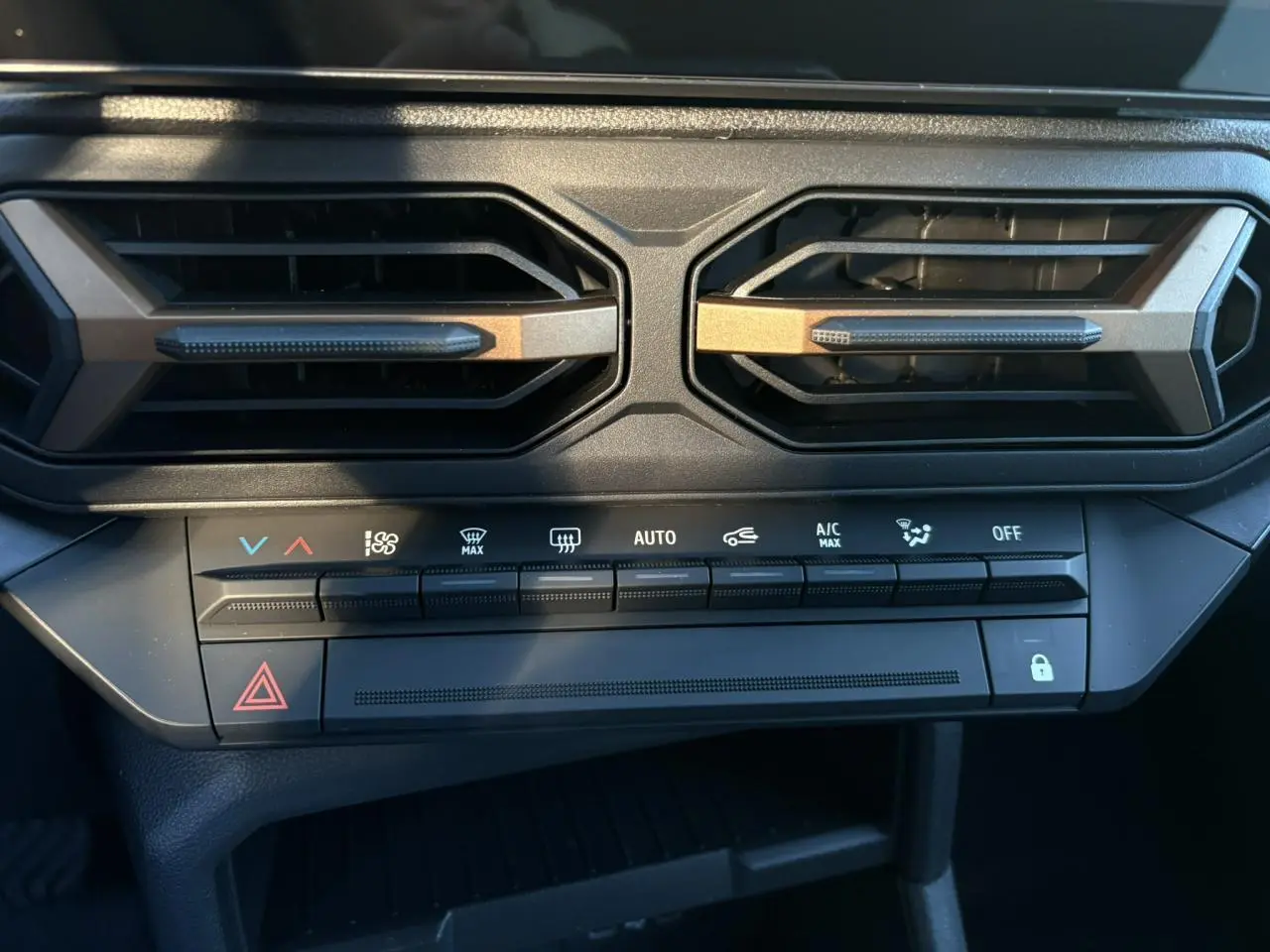 Détail du tableau de bord du Dacia Duster 2025, montrant les aérateurs hexagonaux et les commandes de climatisation.