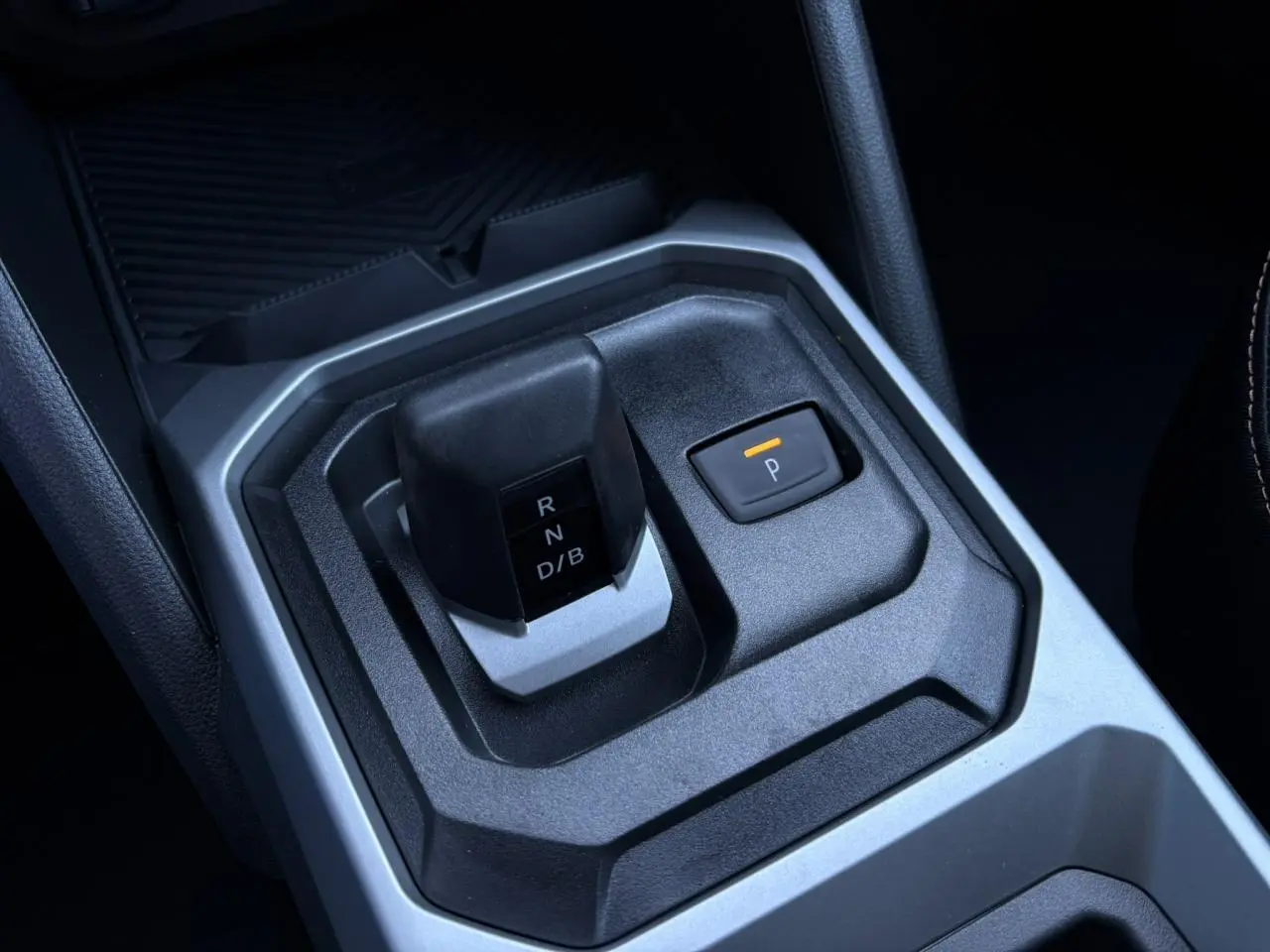 Gros plan sur le levier de vitesses et bouton de frein à main électrique du Dacia Duster gris Schiste, intérieur moderne.