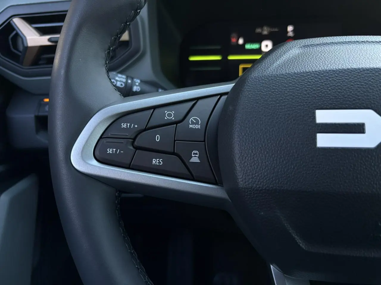 Gros plan sur la partie gauche du volant noir du Dacia Duster 2025, avec commandes de régulateur de vitesse.