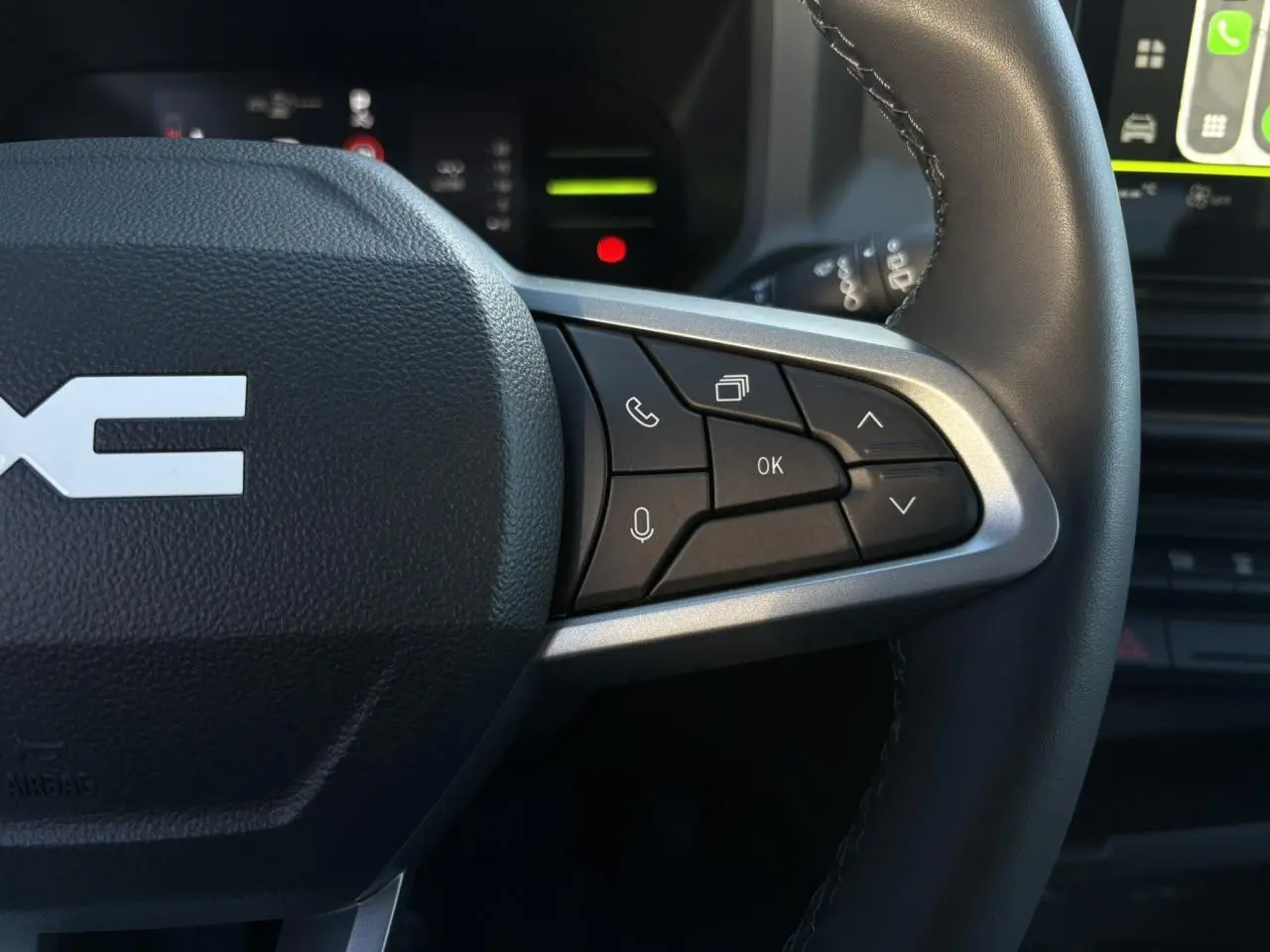 Gros plan sur le côté droit du volant noir du Dacia Duster 2025 avec commandes multifonctions et détails argentés.