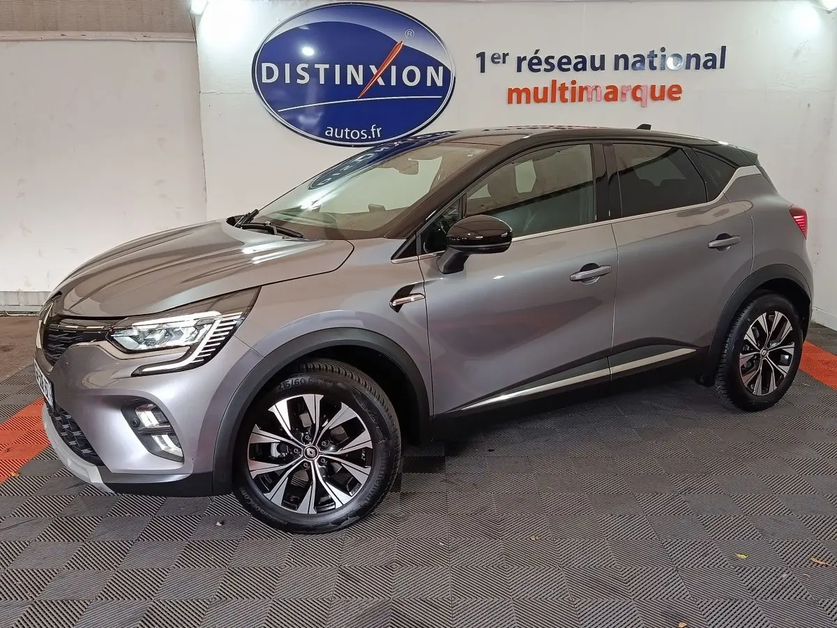 Renault Captur Techno TCe 90 gris foncé vu de profil côté gauche, avec jantes alliage et feux LED allumés.