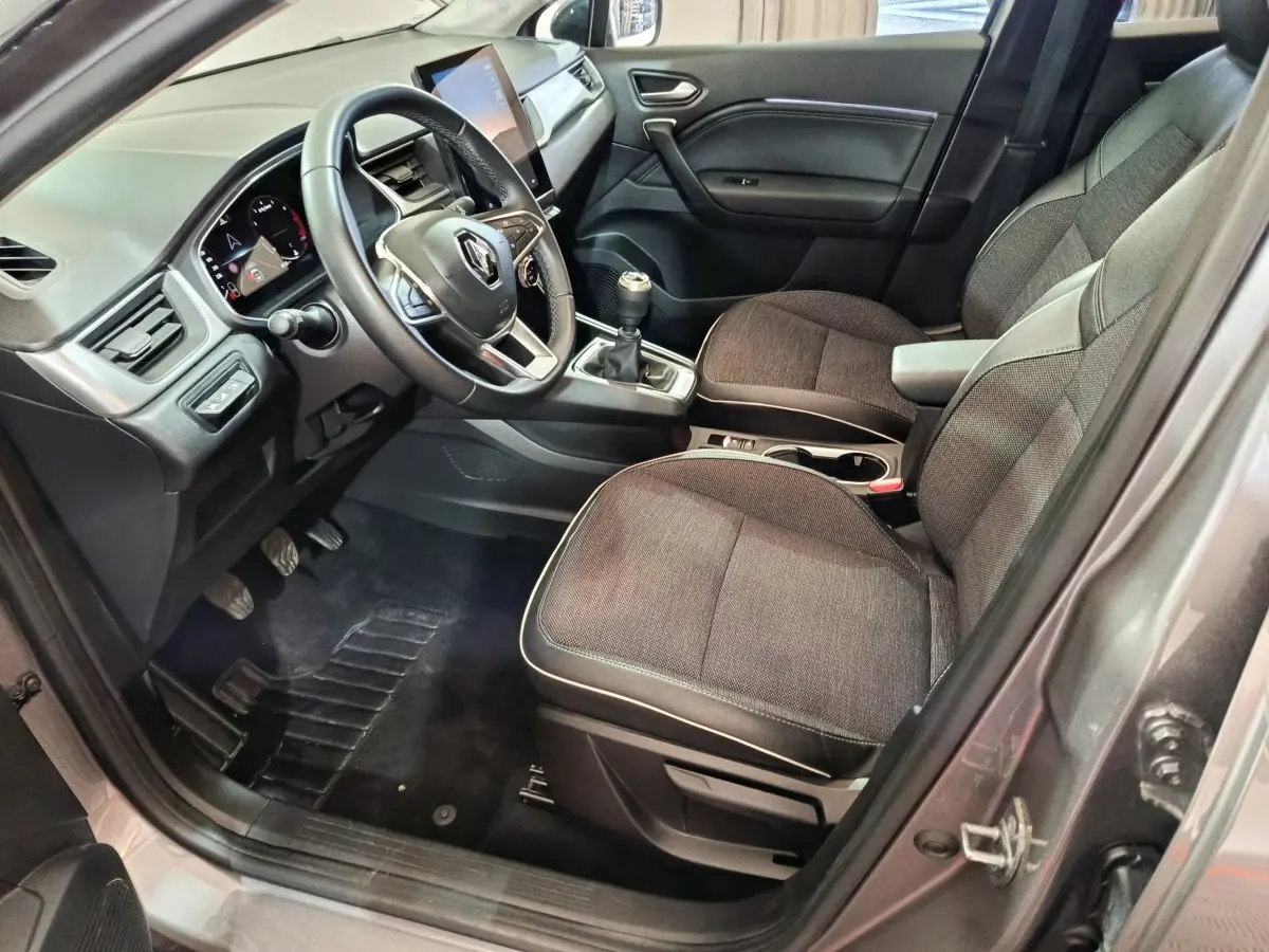 Intérieur côté conducteur du Renault Captur gris foncé 2024, volant multifonctions et écran tactile vertical visible.