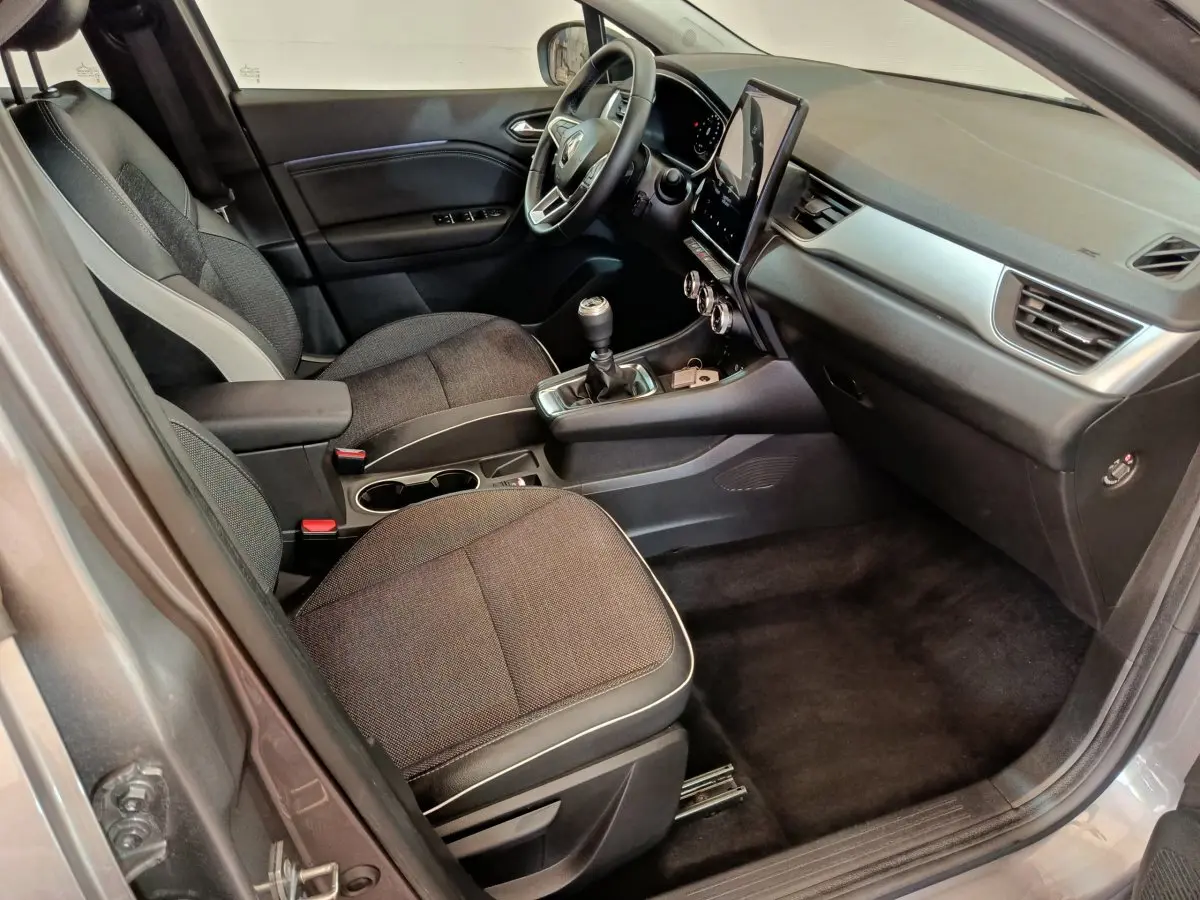 Intérieur avant droit du Renault Captur gris foncé 2024, avec tableau de bord moderne et écran tactile vertical.