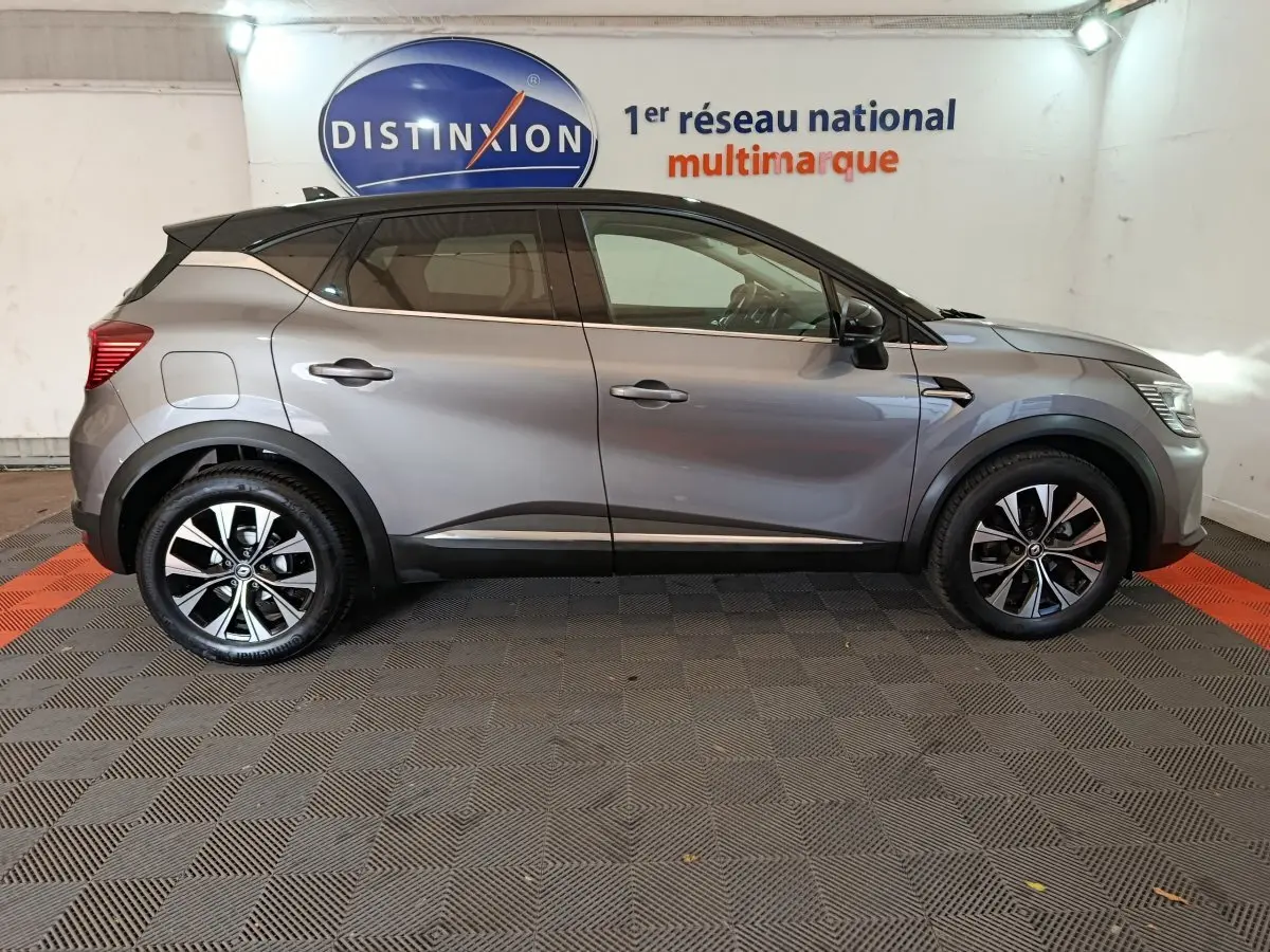 Profil côté gauche d'un Renault Captur Techno TCe 90 gris foncé 2024 avec jantes alliage et toit noir contrasté.