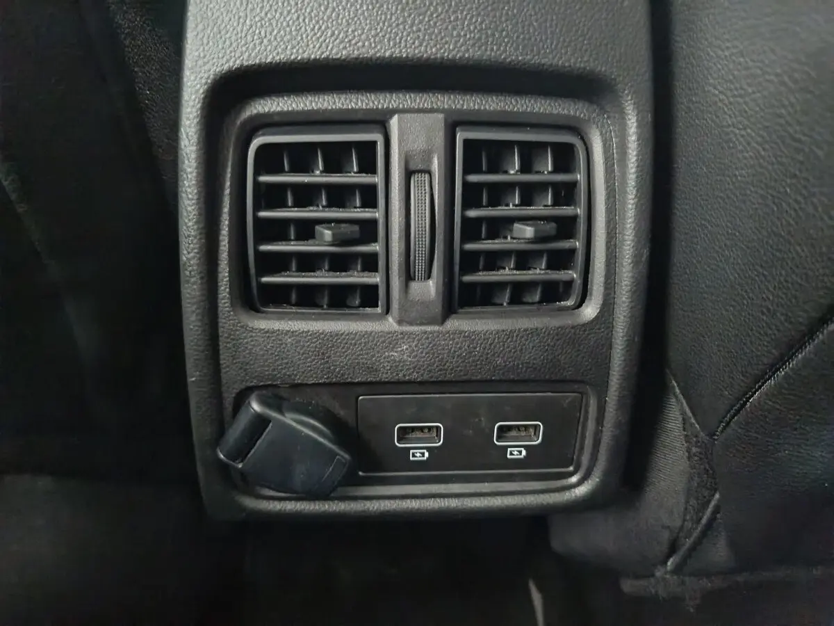 Prise USB double et prise 12V sous les aérateurs arrière noirs dans l'habitacle du Renault Captur gris foncé 2024.