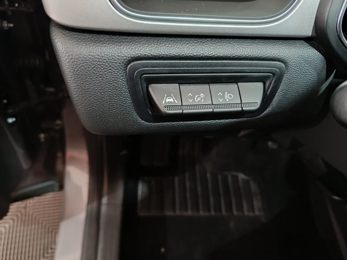 Boutons de réglage de l'aide à la conduite et des phares sur le tableau de bord côté conducteur d'un Renault Captur gris foncé.