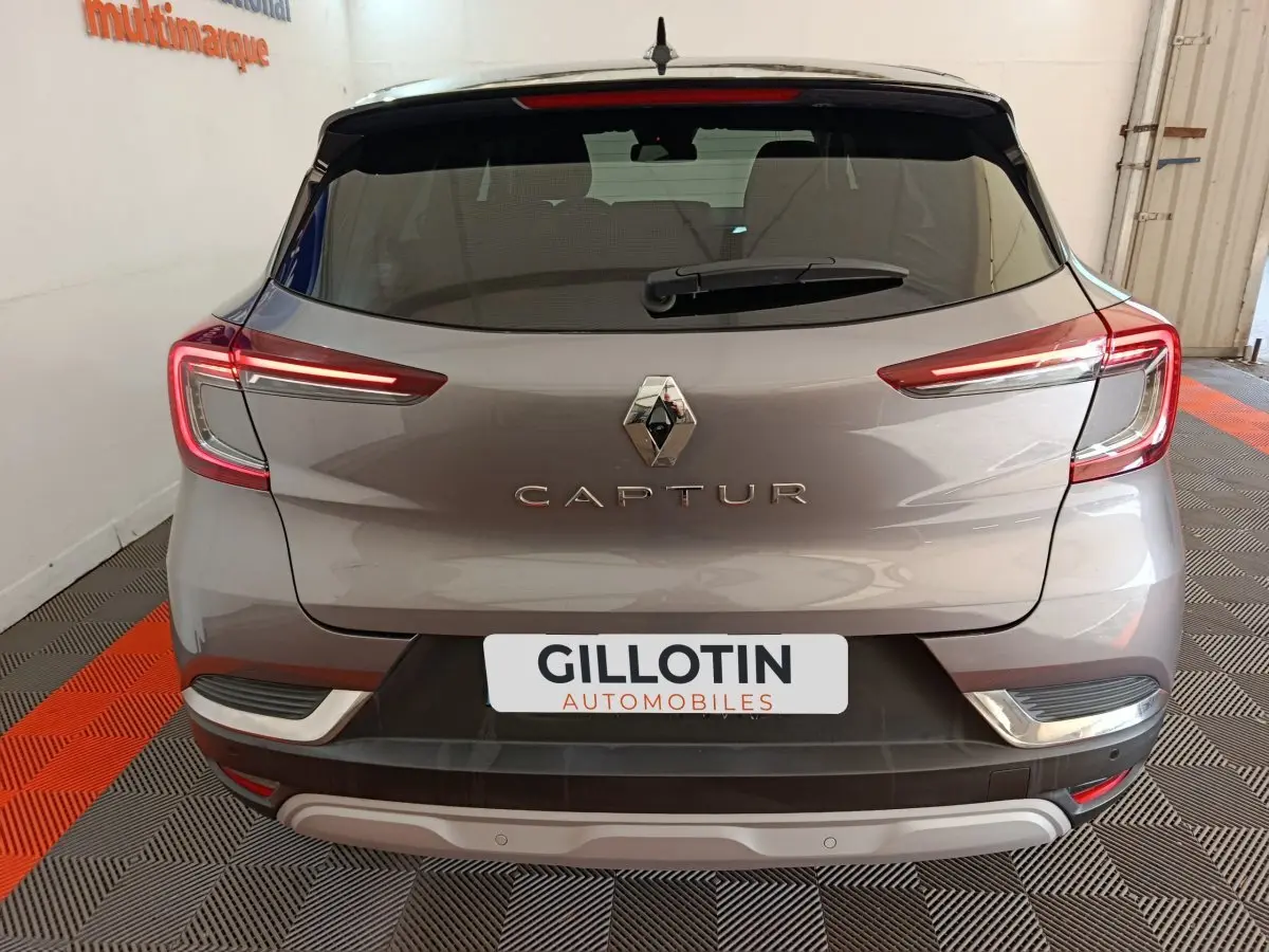 Vue arrière d'un Renault Captur gris foncé 2024 avec feux LED allumés et logo centré sur le hayon.