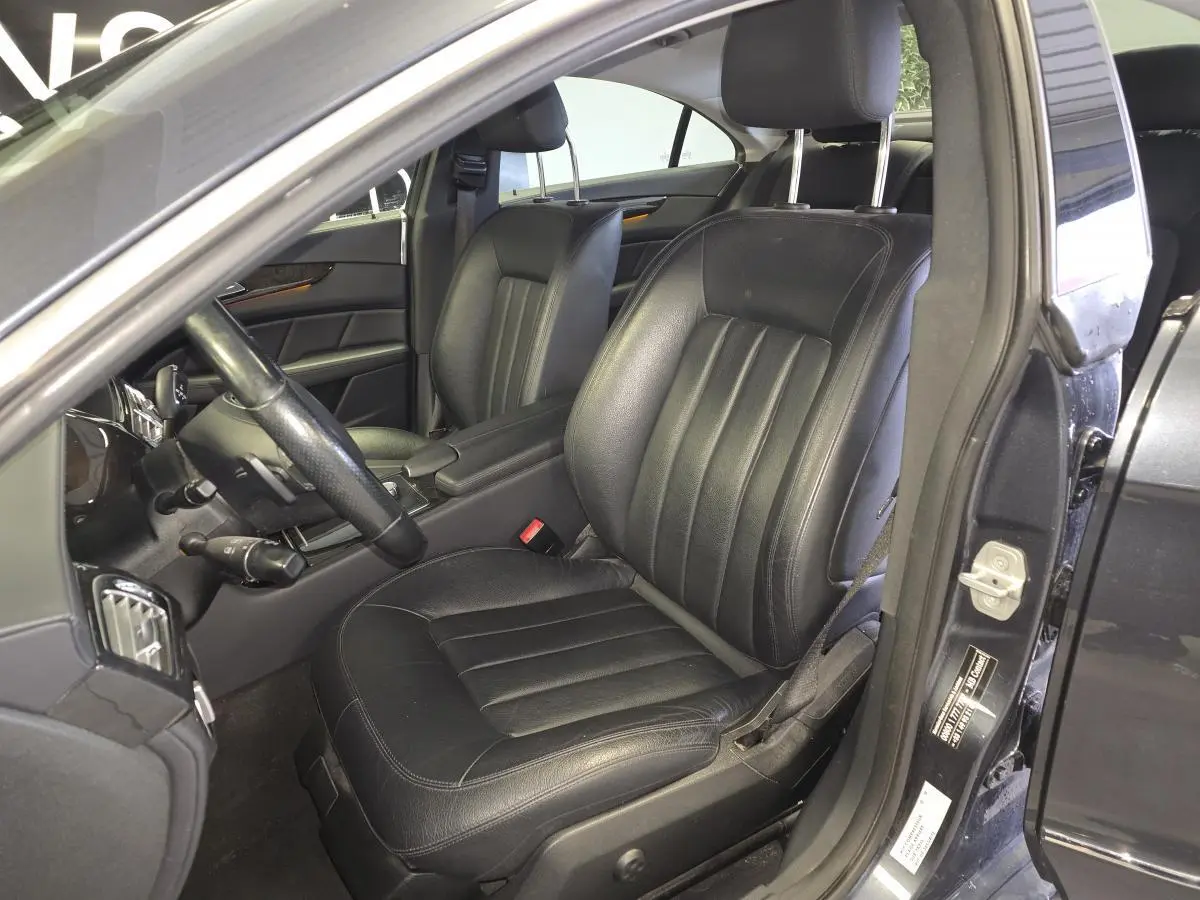 Vue intérieure côté conducteur d'une Mercedes Classe CLS 250 CDI gris avec sièges en cuir noir et volant multifonctions.