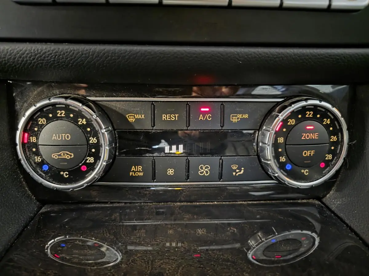 Gros plan sur la commande de climatisation automatique 3 zones de la Mercedes CLS 250 CDI gris, avec affichage digital et boutons rétroéclairés.