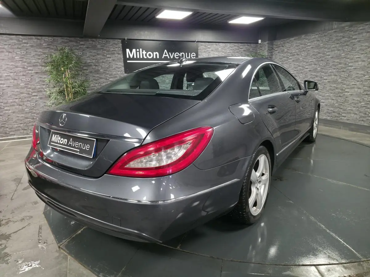 Mercedes Classe CLS gris métallisé vue 3/4 arrière droit avec jantes alliage 5 branches en intérieur showroom.