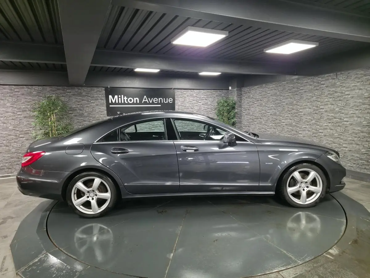 Profil droit d'une Mercedes Classe CLS 250 CDI gris métallisé avec jantes alliage 5 branches en showroom.