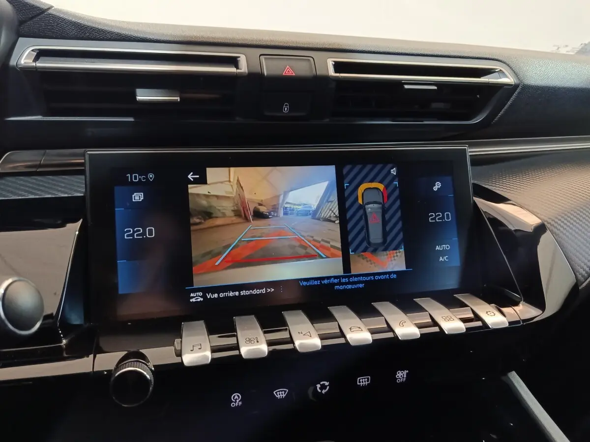 Vue rapprochée de l’écran tactile central du tableau de bord de la Peugeot 508 gris clair, affichant la caméra de recul et les commandes climatisation.