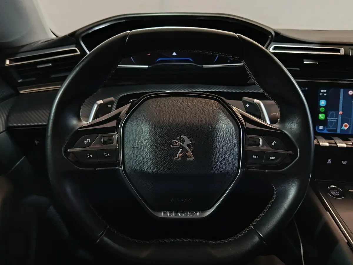Vue rapprochée du volant cuir noir de la Peugeot 508 2020 avec commandes intégrées et tableau de bord numérique.