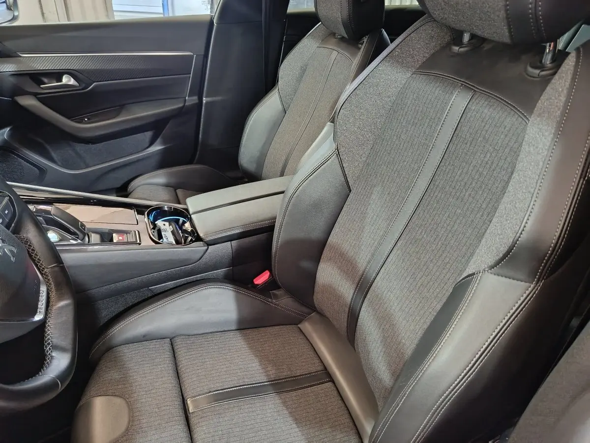 Vue intérieure côté conducteur de la Peugeot 508 gris clair, sièges tissu et cuir avec console centrale moderne.