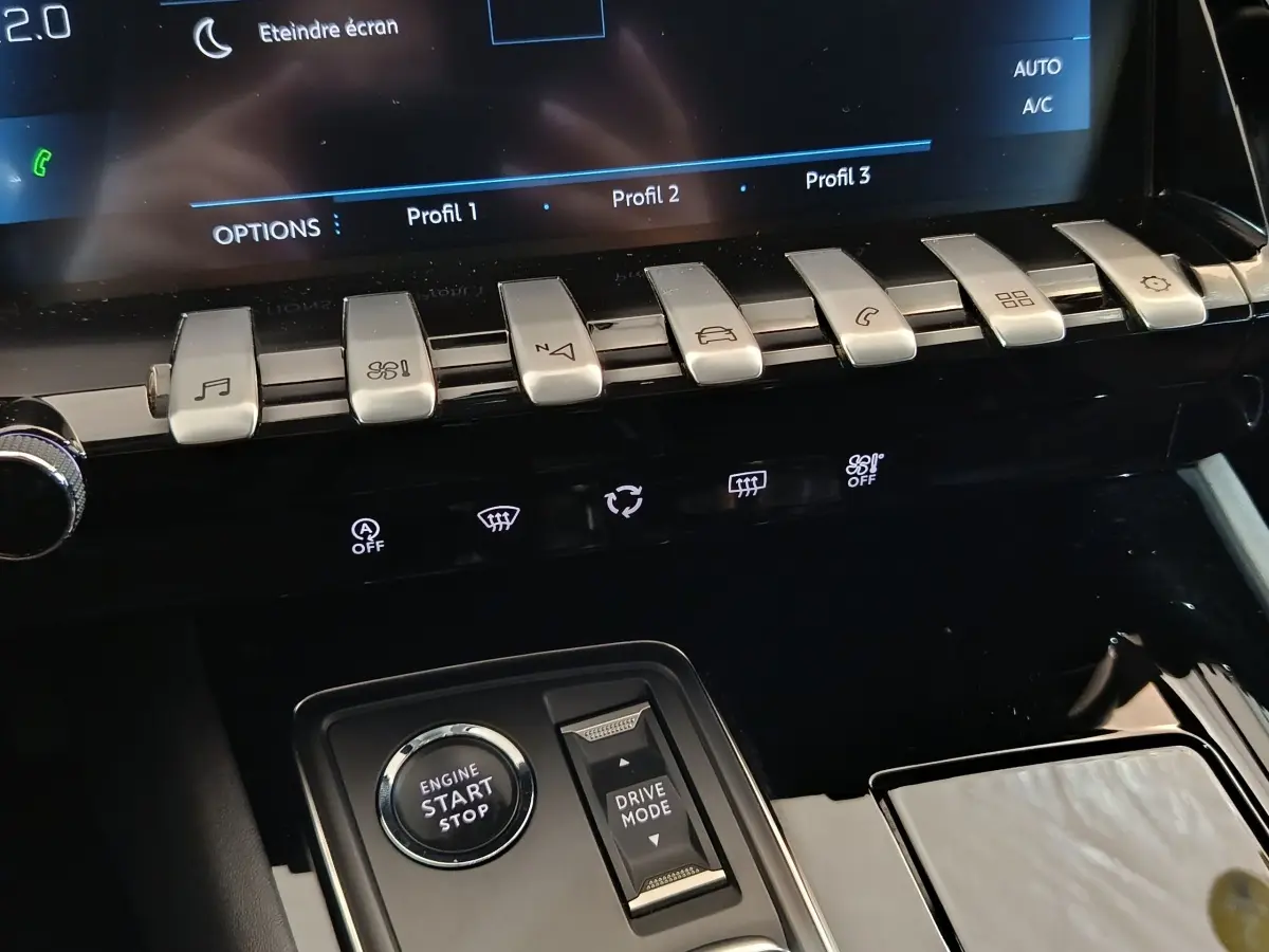 Gros plan sur la console centrale noire du Peugeot 508 gris clair, avec boutons piano et démarrage moteur visible.