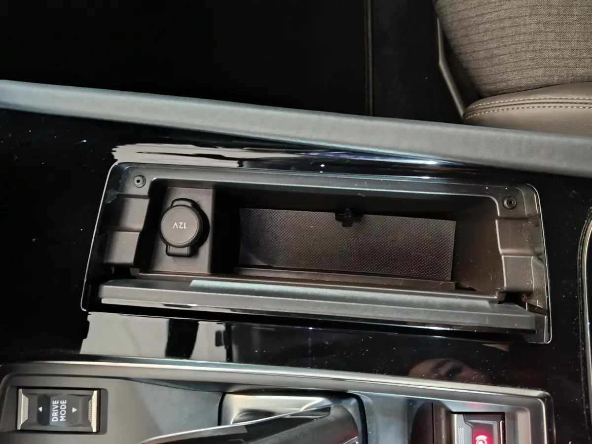 Gros plan sur la console centrale noire brillante de la Peugeot 508 gris clair, avec prise 12V et bouton Drive Mode visible.