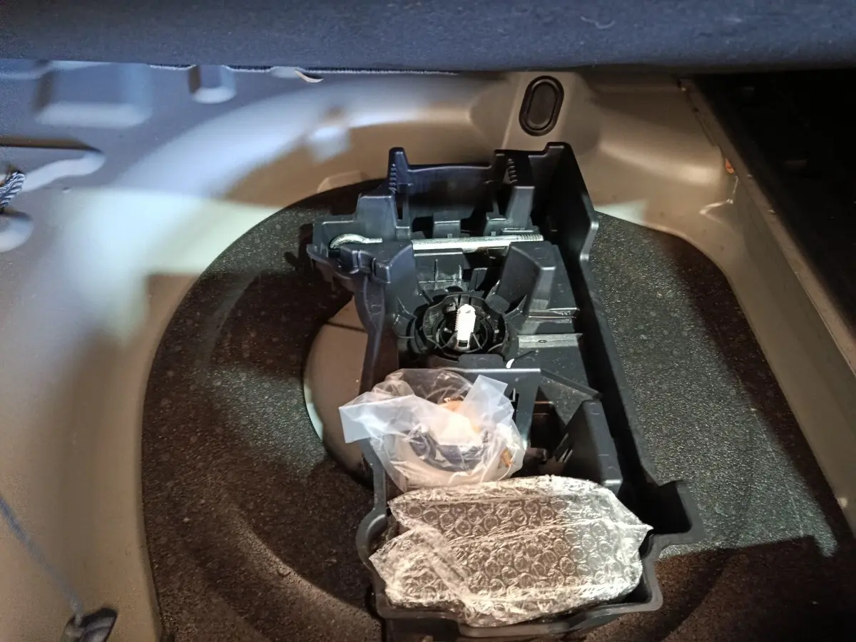 Vue rapprochée de la roue de secours et du rangement à outils dans le coffre gris clair d’une Peugeot 508 2020.