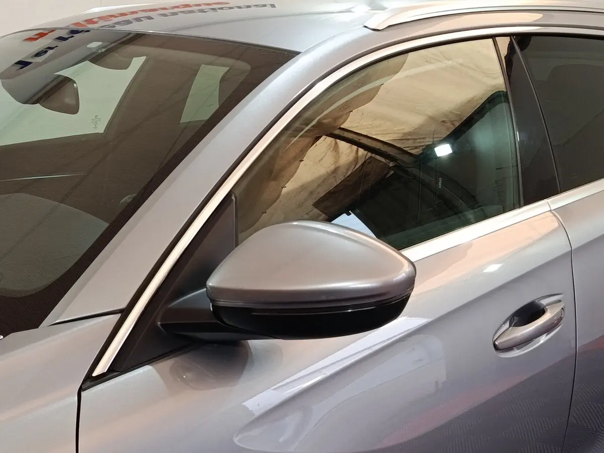 Vue rapprochée côté gauche d'une Peugeot 508 gris clair, mettant en valeur le rétroviseur et la poignée de porte.