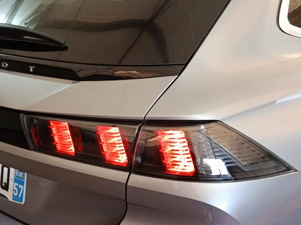 Feu arrière droit allumé sur Peugeot 508 gris clair vue en gros plan, soulignant la ligne de coffre et la lunette arrière.