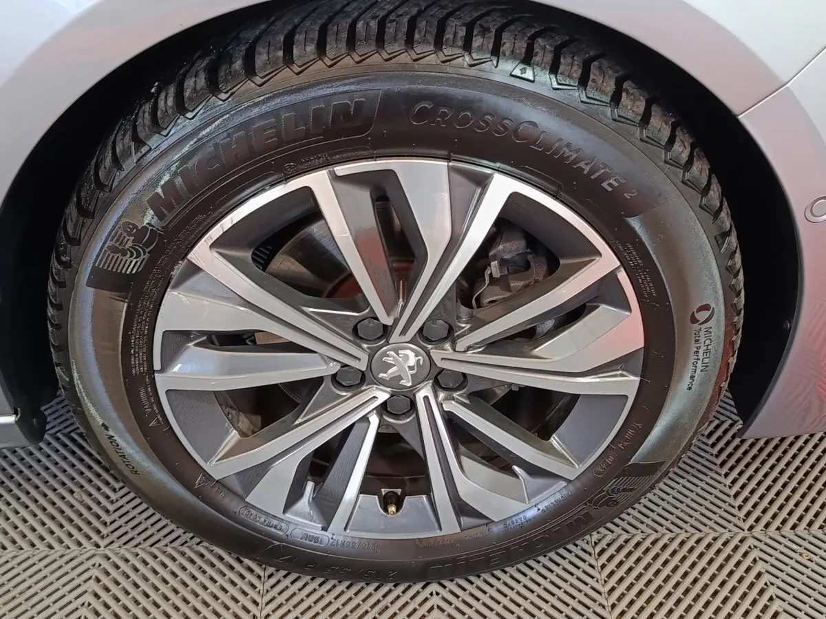 Gros plan sur la roue avant droite gris clair d'une Peugeot 508 avec jante alliage et logo Peugeot central.